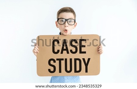 Young caucasian boy smiling while holding a card with text CASE STUDY on a white plain background