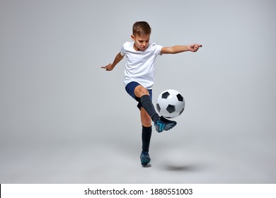young caucasian boy with soccer ball doing flying kick isolated in studio, athletic sportive boy in uniform - Powered by Shutterstock