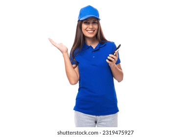 young caucasian brunette advertiser woman in blank blue t-shirt and cap with phone