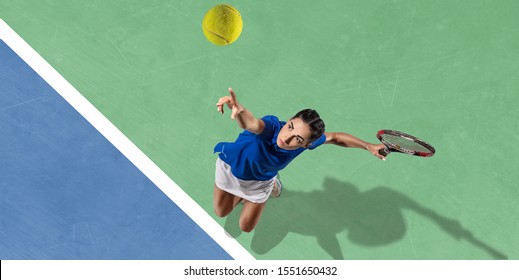 Young caucasian brunette woman in blue shirt playing tennis at the court. Hits ball with racket, outdoors. Youth, flexibility, power, energy. Copyspace. Top view. Motion, action, healthy lifestyle. - Powered by Shutterstock