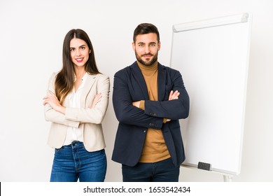 Young caucasian business couple isolated who feels confident, crossing arms with determination.