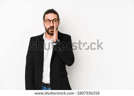 Young caucasian business man isolated on a white background is saying a secret hot braking news and looking aside
