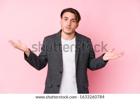 Young caucasian business man posing isolated doubting and shrugging shoulders in questioning gesture.