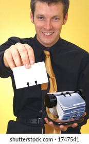 Young Caucasian Business Man With A Rolodex Card. Focus On Card.