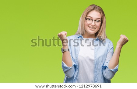Young caucasian business woman wearing glasses over isolated background celebrating surprised and amazed for success with arms raised and open eyes. Winner concept.