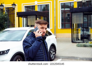 Young Caucasian Businessman 34 Years Old Man With Goatee Beard Talks On Smartphone On Street Near White Car. Waist Up Lifestyle Business Portrait, Success Concept.