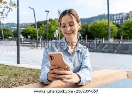 Young Caucasian businesswoman gazes into her mobile phone in an outdoor urban setting. Her focused expression provide a modern and dynamic portrayal of the contemporary business world, with copyspace.