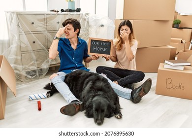 Young Caucasian Couple With Dog Holding Our First Home Blackboard At New House Smelling Something Stinky And Disgusting, Intolerable Smell, Holding Breath With Fingers On Nose. Bad Smell 