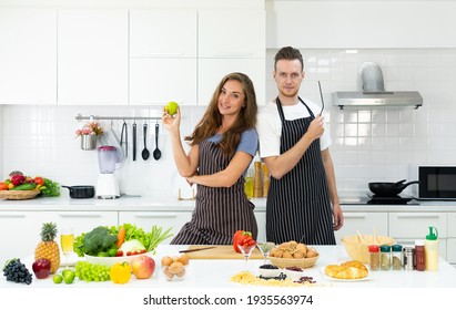 young caucasian couple holding bowl of fruit and vegetable in hand and standing in kitchen to prepare breakfast. family together concept