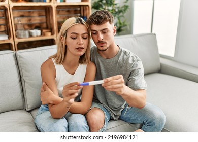 Young caucasian couple with serious expression holding pregnacy test at home. - Powered by Shutterstock