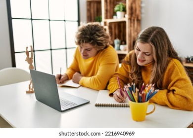 Young Caucasian Couple Smiling Confident Having Online Art Class At Home