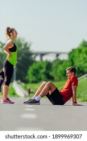 Young caucasian couple taking a break on the running road track and resting after running.