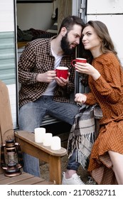 Young Caucasian Couple Is Traveling In Travel Van. Romantic Atmosphere Of Relaxation. Road Trip Around Country For The Weekend. Man And Woman Sitting In Camper And Drinking Tea. Millennial Generation