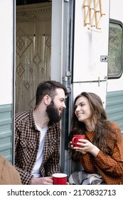 Young Caucasian Couple Is Traveling In Travel Van. Romantic Atmosphere Of Relaxation. Road Trip Around Country For The Weekend. Man And Woman Sitting In Caravan And Drinking Tea. Millennial Generation