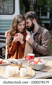 Young Caucasian Couple Is Traveling In Travel Van. Romantic Atmosphere Of Relaxation. Road Trip Around Country For The Weekend. Boyfriend Embrace Girl Near Camper And Drinking Tea Or Mulled Wine