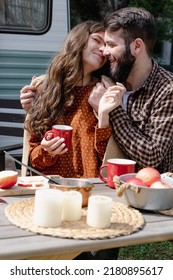 Young Caucasian Couple Is Traveling In Van. Romantic Atmosphere Of Relaxation. Road Trip Around Country For The Weekend. Happy Loving Man And Woman Embrace Near Camper And Drinking Tea Or Mulled Wine