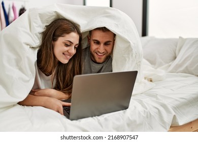 Young Caucasian Couple Watching Movie Using Laptop Lying In Bed.