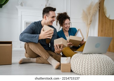 Young Caucasian Couple Woman And Man Wife And Husband Or Girlfriend And Boyfriend Opening Gifts Box Presents In Front Of Laptop Computer At Home Having Online Video Call Copy Space