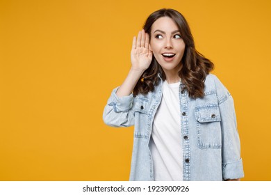 Young Caucasian Curious Brunette Fun Nosy Woman 20s Wearing Casual Stylish Denim Shirt White T-shirt Trying To Hear You Overhear Listening Intently Isolated On Yellow Color Background Studio Portrait