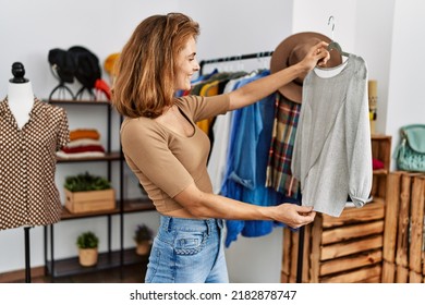 Young Caucasian Customer Woman Smiling Happy Holding Hanger With Clothes At Clothing Store.