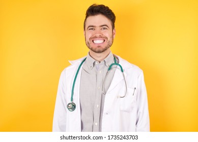 Young Caucasian Doctor Man Wearing Medical Uniform, Over Isolated Yellow Background With A Happy And Cool Smile On Face. Lucky Person.