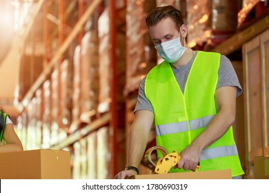 Young Caucasian Employee Male Packing Cardboard Box With Scotch Tape, Wearing Protective Face Mask, New Normal After Pandemic Crisis.