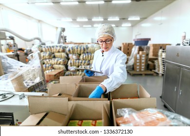 Young Caucasian Employee In Sterile Uniform Using Tablet For Logistic. Food Factory Interior.