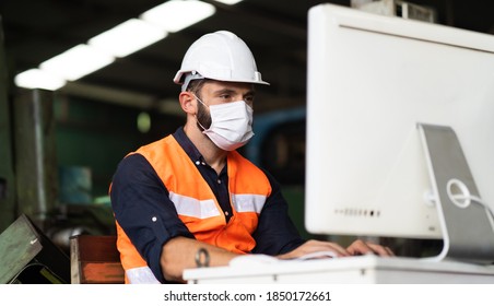 Young Caucasian Engineering Man Worker Working On Digital Tablet Computer At Manufacturing. Worker Man Wearing Face Mask Prevent Covid-19 Virus And Protective Hard Hat. 