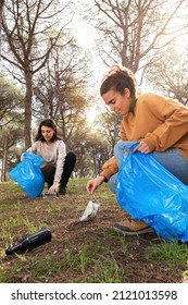 Young Caucasian Environmental Activist Women Pick Up Garbage To Clean Forest. Vertical Image.