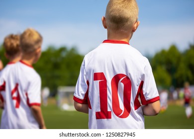 Young Caucasian European Soccer Players Waiting On Soccer Bench And Watching Football Game. Youth Soccer Horizontal Image With Blurred Background