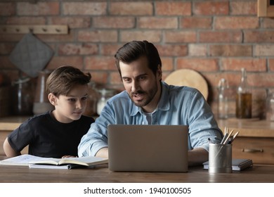 Young Caucasian father help little son prepare homework study online on laptop together. Caring dad and small boy child do home task learn have webcam class on computer. Education concept. - Powered by Shutterstock