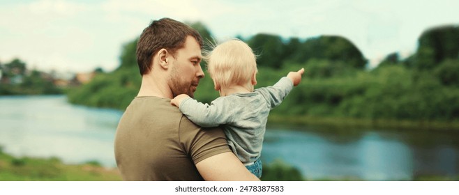 Young caucasian father holding his son, dad and child walking together in summer park - Powered by Shutterstock