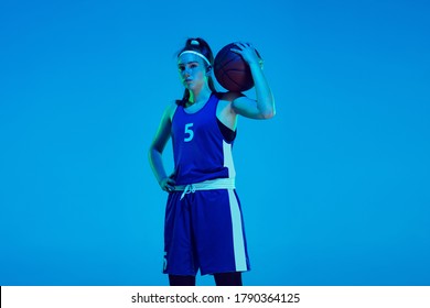 Young caucasian female basketball player of team posing confident with ball isolated on blue background in neon light. Concept of sport, movement, energy and dynamic, healthy lifestyle. Training. - Powered by Shutterstock