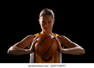 Young Caucasian female basketball player poses confidently in basketball attire on a black background. She exudes determination and strength, ready for a competitive game. - Powered by Shutterstock