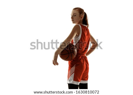 Young caucasian female basketball player posing confident isolated on white background. Redhair sportive girl. Concept of sport, movement, energy and dynamic, healthy lifestyle. Training, practicing.