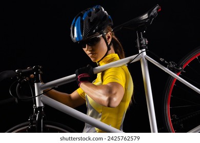 Young Caucasian female cyclist prepares her bicycle for a night ride, with copy space. She's dressed in cycling gear, highlighting the active lifestyle. - Powered by Shutterstock