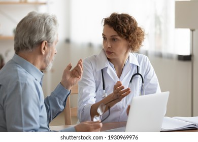 Young Caucasian female doctor in white uniform consult senior male patient at meeting in private clinic. Caring woman GP talk speak with mature man at consultation in hospital. Geriatrics concept. - Shutterstock ID 1930969976