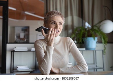 Young Caucasian Female Employee Sit At Workplace Talk Speak On Speakerphone On Cellphone. 30s Businesswoman Record Audio Message Or Smartphone, Use Virtual Digital Voice Assistant On Modern Gadget.