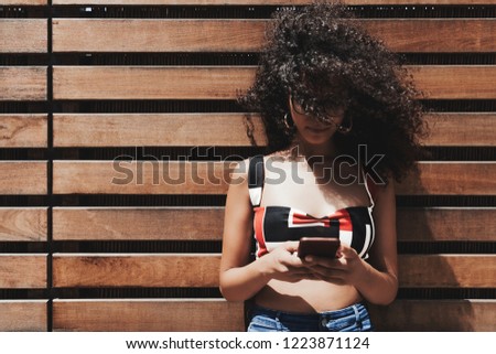 Similar – Frau mit Afro-Haaren auf der Straße, die ein Smartphone hält.