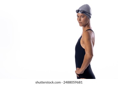 Young Caucasian female swimmer in swimwear poses confidently on a white background, with copy space. Her athletic form and swim cap suggest a professional swimmer's portrait. - Powered by Shutterstock