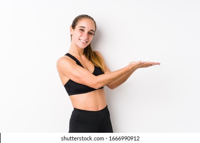 Young caucasian fitness woman posing in a white background holding a copy space on a palm. - Shutterstock ID 1666990912