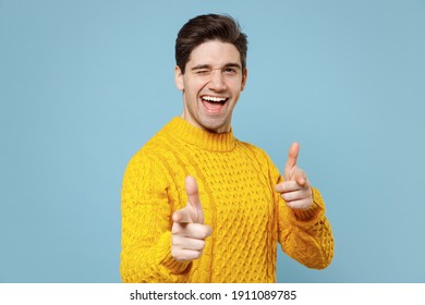 Young Caucasian Friendly Leader Smiling Man 20s In Casual Knitted Cozy Yellow Fashionable Sweater Point Index Fingers Camera On You Motivating Blink Yisolated On Blue Color Background Studio Portrait.