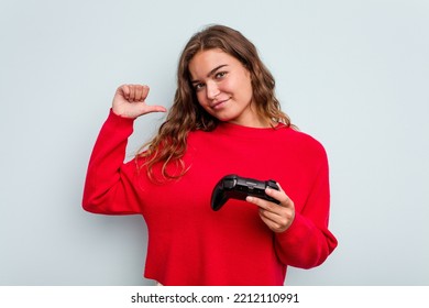 Young Caucasian Gamer Woman Holding A Game Controller Isolated On Blue Background Feels Proud And Self Confident, Example To Follow.