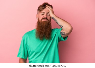 Young caucasian ginger man with long beard isolated on pink background tired and very sleepy keeping hand on head.