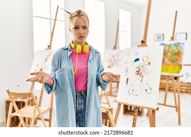 Young Caucasian Girl At Art Studio Clueless And Confused With Open Arms, No Idea Concept. 