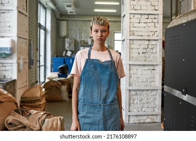 Young Caucasian Girl Barista Or Worker Looking At Camera On Coffee Factory Or Warehouse. Coffee Process Making And Production. Small Business. Modern Automated Manufacturing Equipment