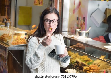 Young Caucasian Girl Eating Spicy Asian Food Near Street Food Booth In Hong Kong. 