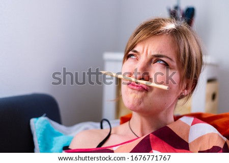Young Caucasian girl is fooling around and home, pencil trapped between nose and lips