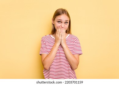 Young caucasian girl isolated on yellow background shocked covering mouth with hands. - Shutterstock ID 2203701159