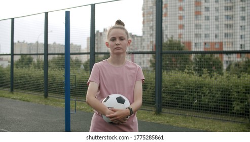 Young caucasian girl practicing soccer skills and tricks, holdind a soccer ball in her hands. Urban city lifestyle outdoors concept - Powered by Shutterstock